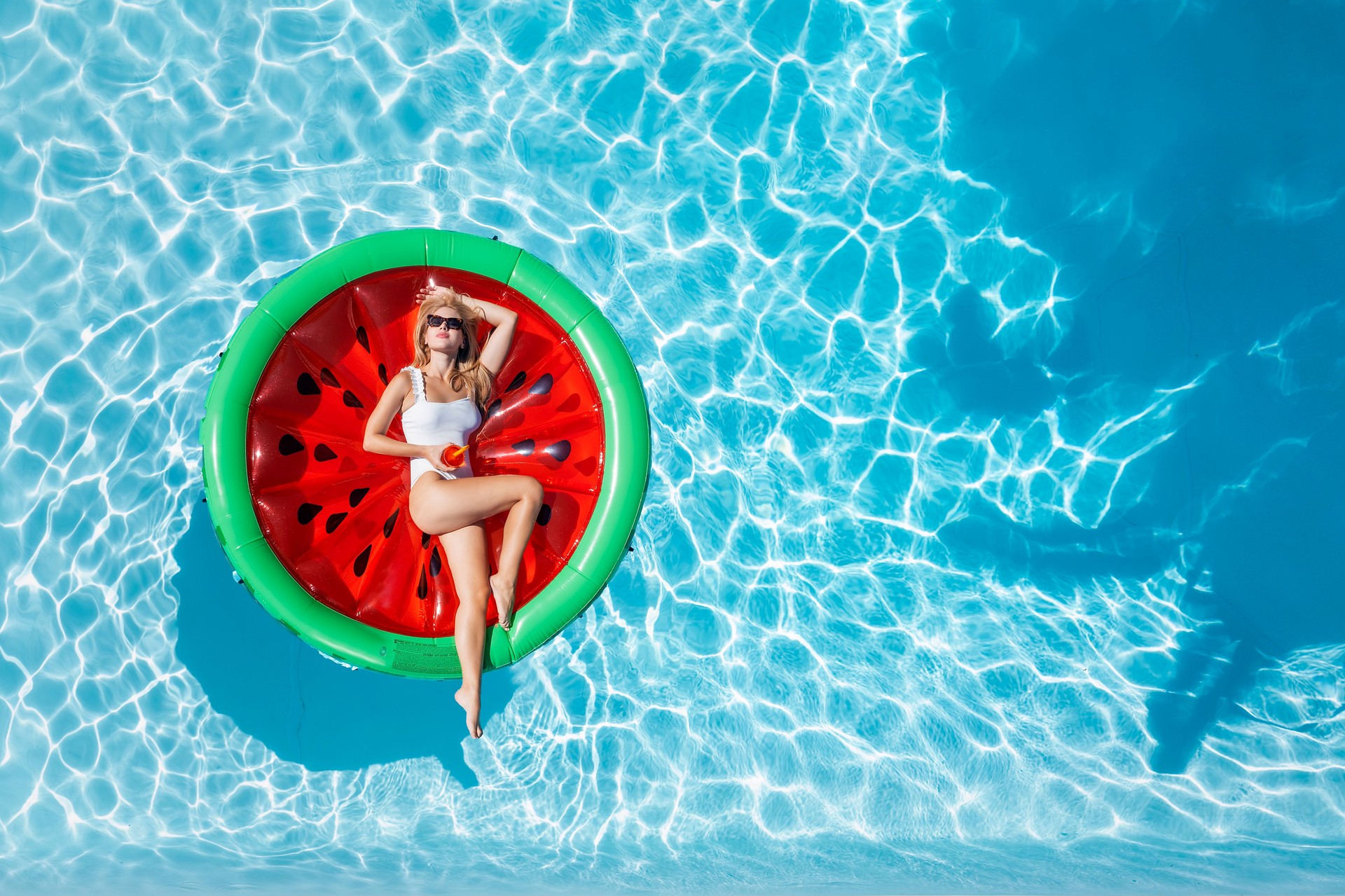 Aerial top down view of a beautiful woman in bikini on a watermelon shaped float